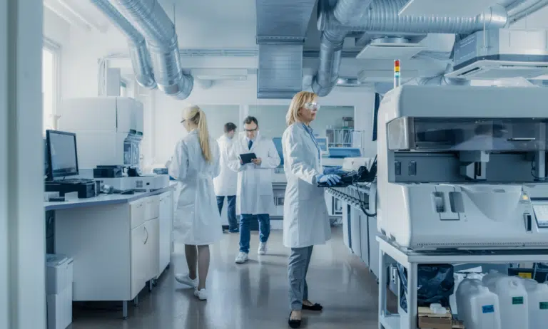 team of research scientists working on computer with medical equipment