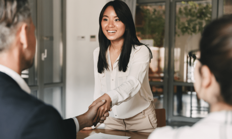 hiring managers sitting at table shaking hands with woman after negotiations