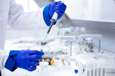 Scientist with blue gloves fills test tube